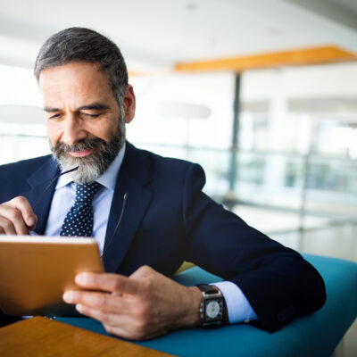 Elegant business multitasking multimedia man using devices at office