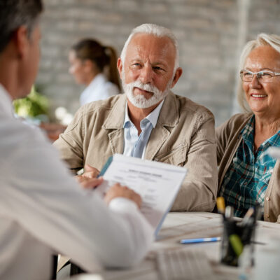 Happy mature couple informing themselves about health insurance while talking to a doctor at clinic.